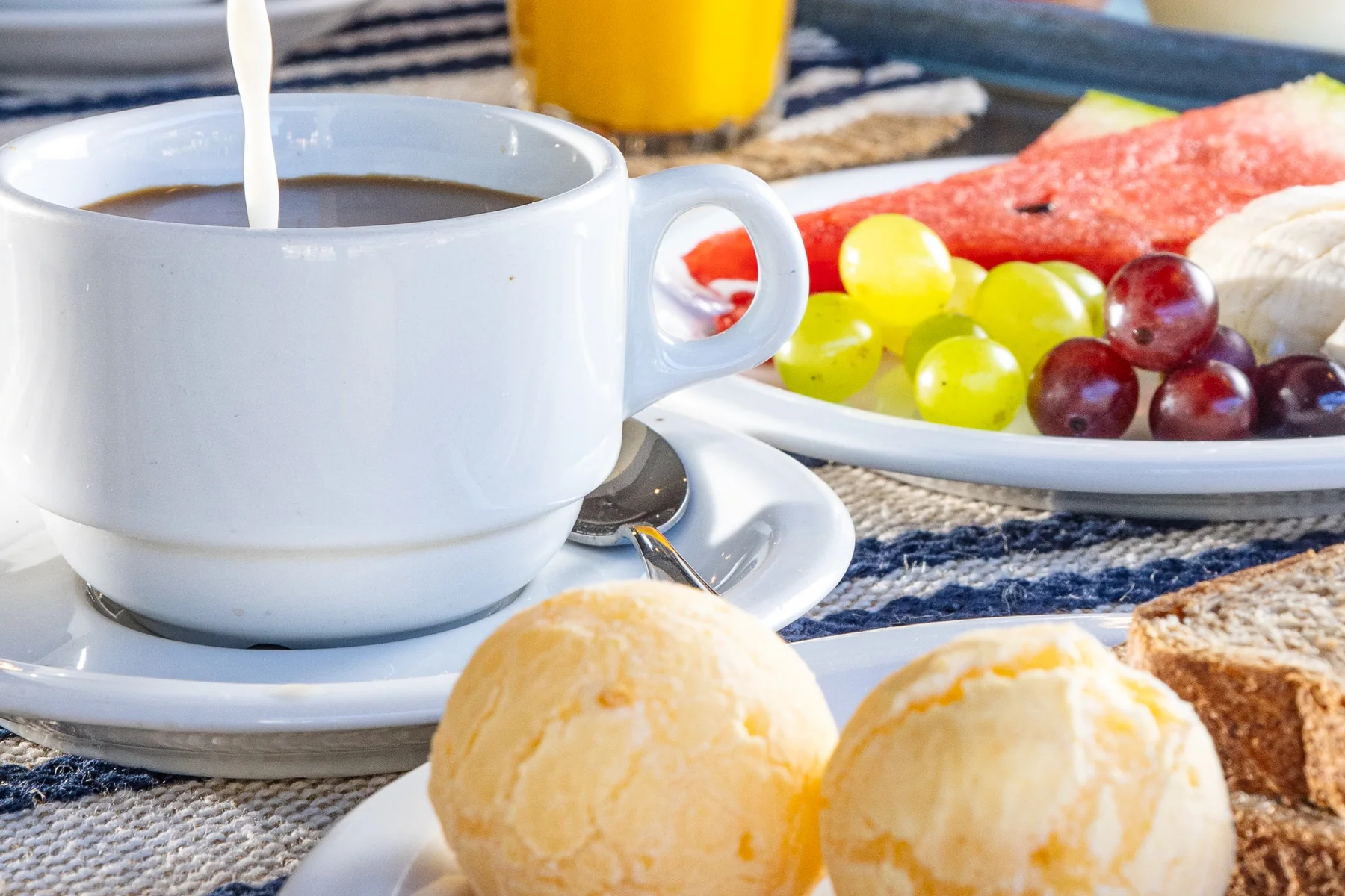 Café com leite, suco de laranja, mel e frutas