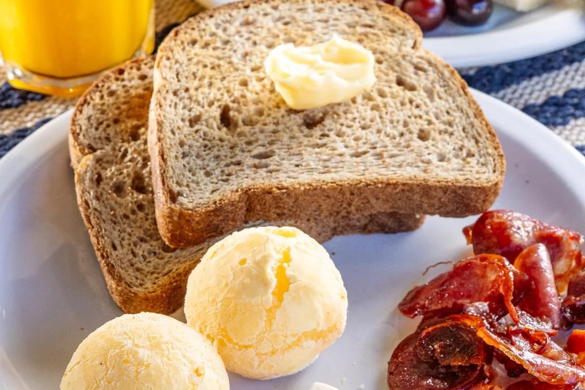 Pão de queijo, pão integral, queijo e frutas