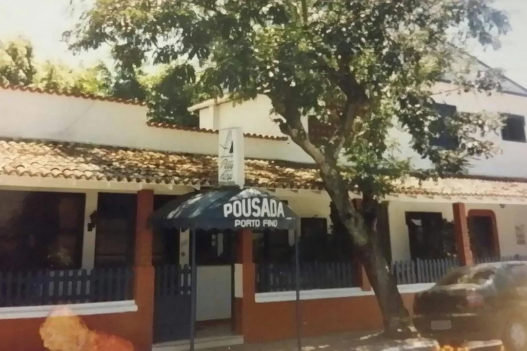 Fachada antiga com toldo azul escrito Pousada Porto Fino