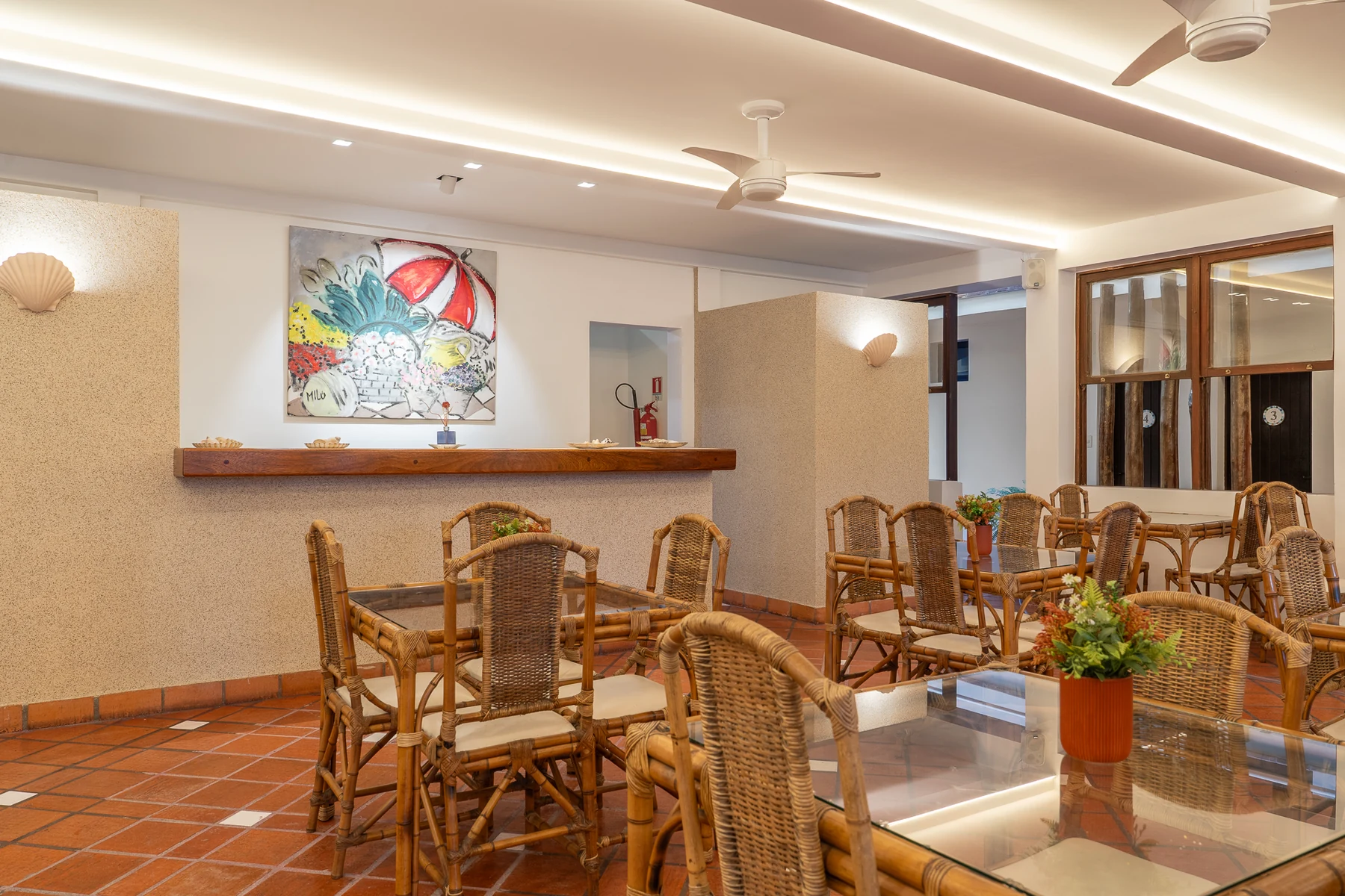Salão do café com mesas de palha, balcão e quadro de guarda-sol