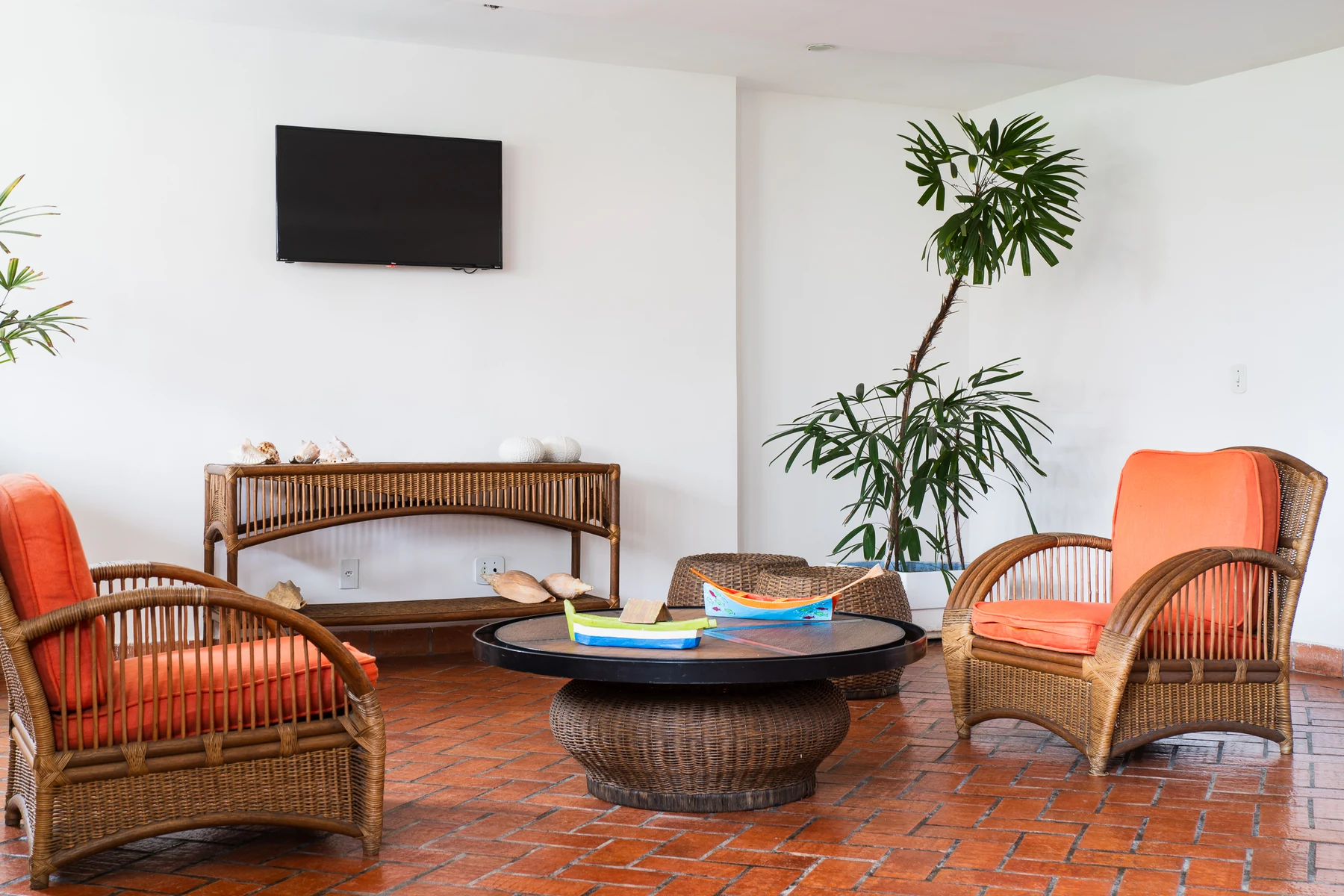 Lounge com poltronas de palha laranja e barquinhos de madeira