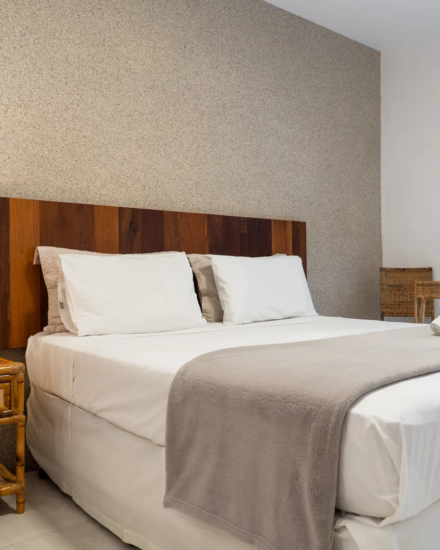 Cama king-size com cabeceira de madeira e mesa de palha