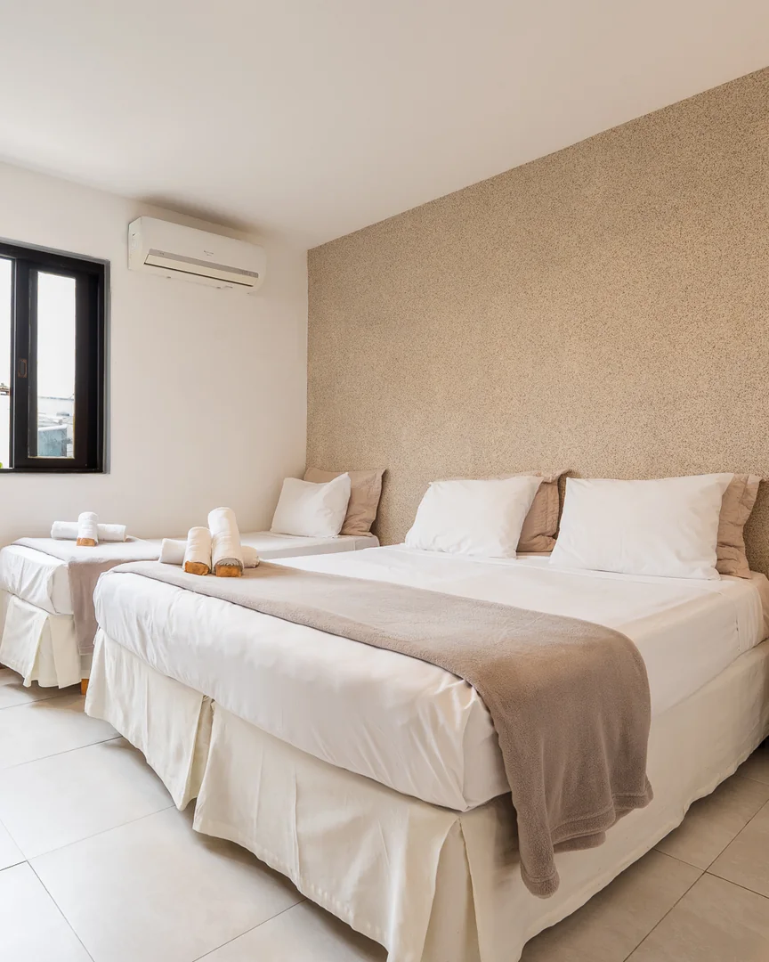 Quarto triplo com cama de casal, cama de solteiro e janela