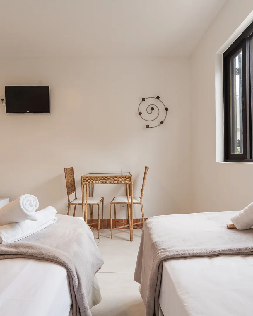 Camas, mesa de palha e TV no quarto triplo