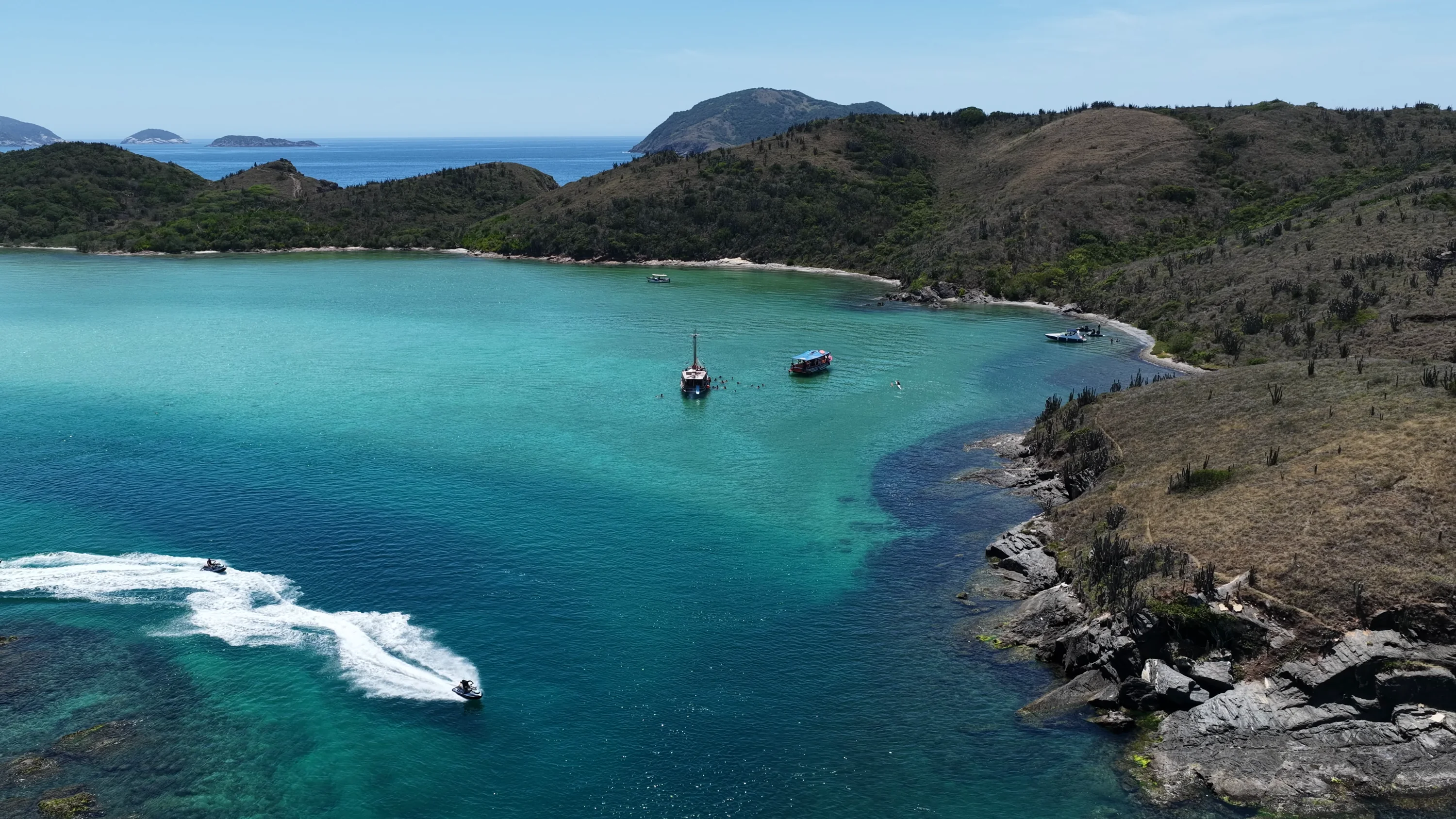 Baía de água turquesa cercada de morros verdes, em Cabo Frio