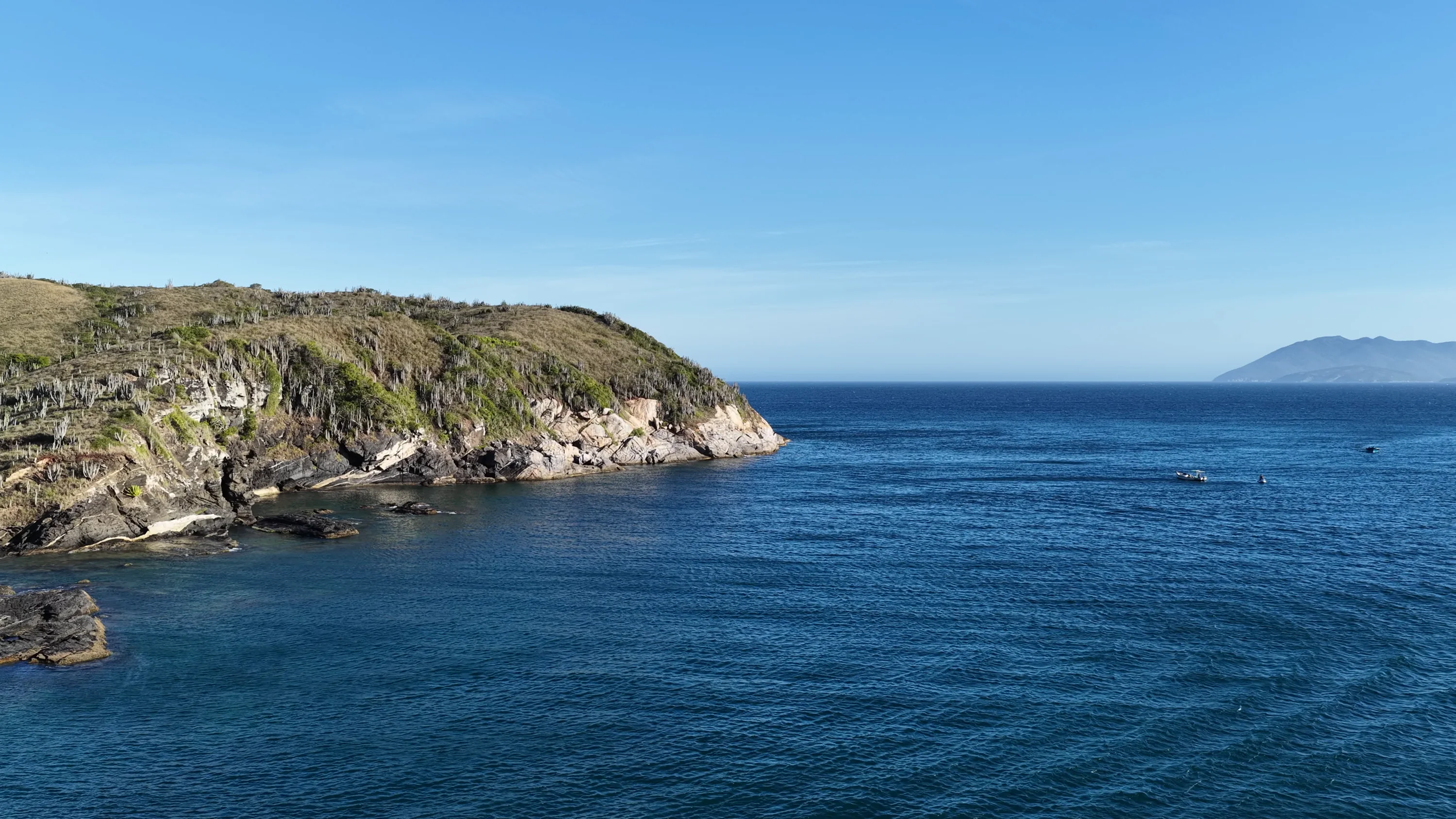 Morro coberto de mata sobre o mar azul